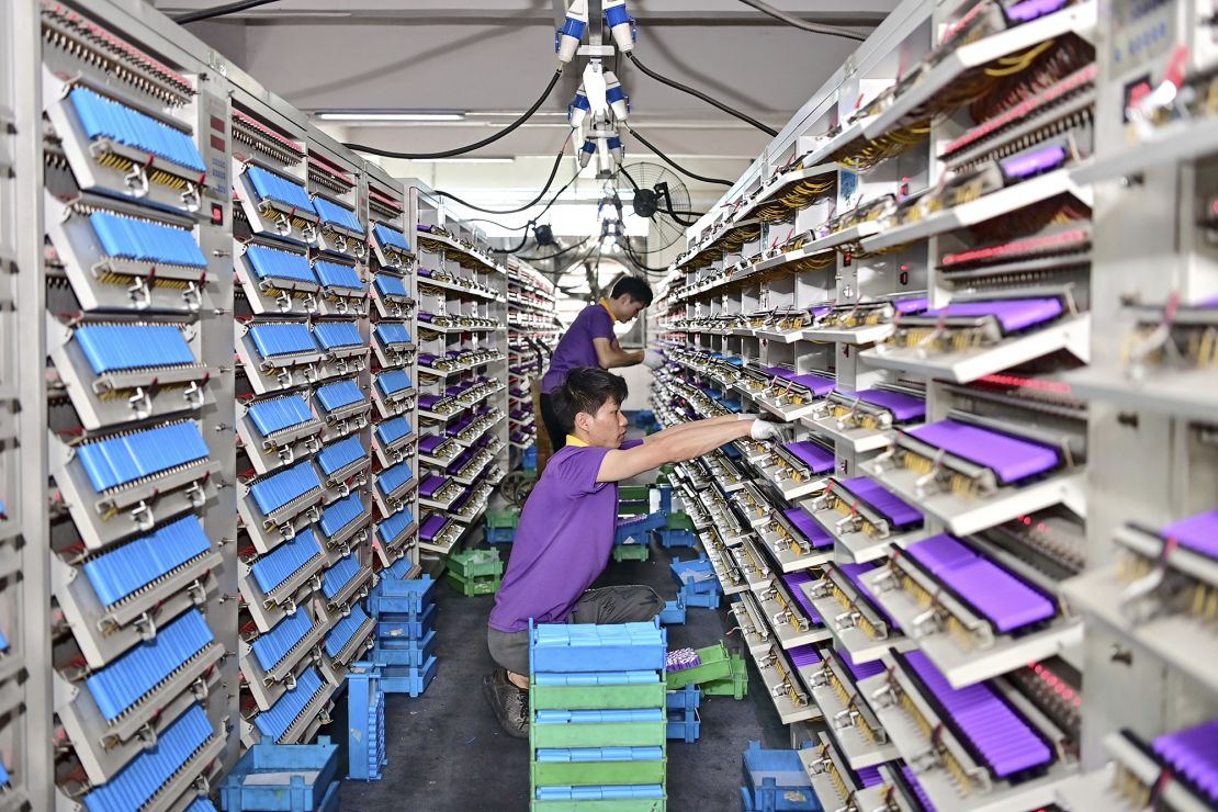 An employee tests cylindrical cells at a factory producing lithium-ion batteries, used in electric vehicles, in June 2024 in Fuzhou, China.