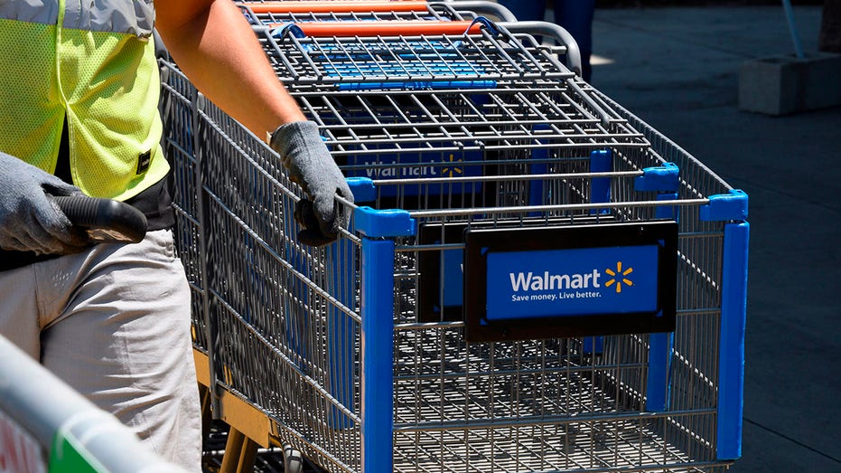 Walmart employee pushing a line of shopping carts
