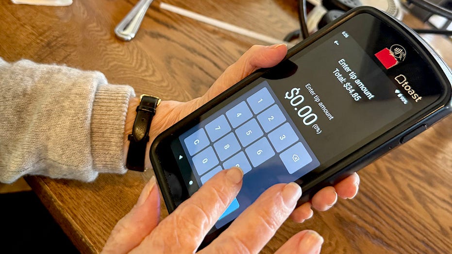 Woman entering tip amount at restaurant using handheld tablet in Florida.