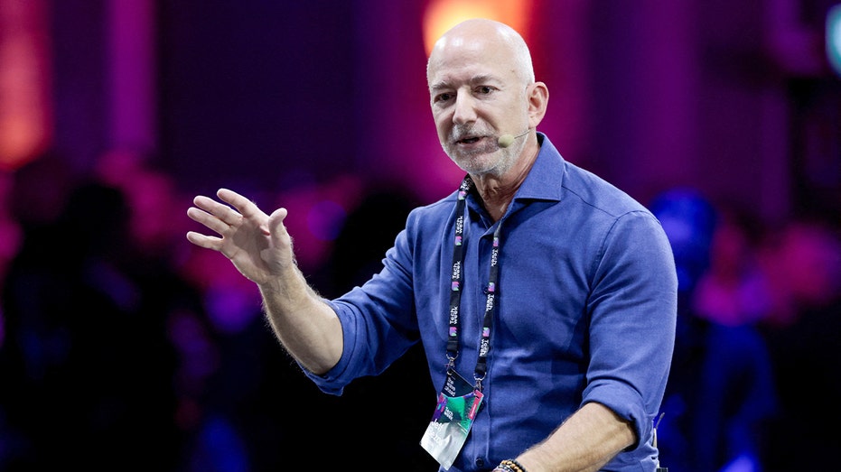 Jeff Bezos speaking on stage while gesturing during a conference discussion.