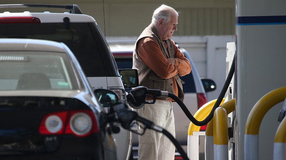 A man stands at a gas station.